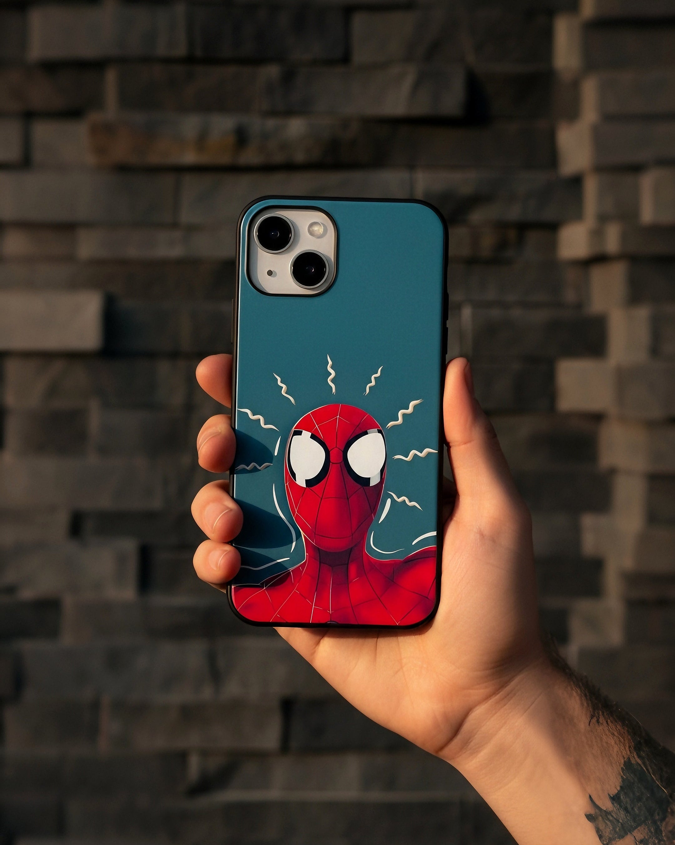 Phone case with Spider-Man design held by a person against a brick wall.