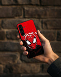 Hand holding a smartphone with a red and black superhero-themed case against a brick wall.