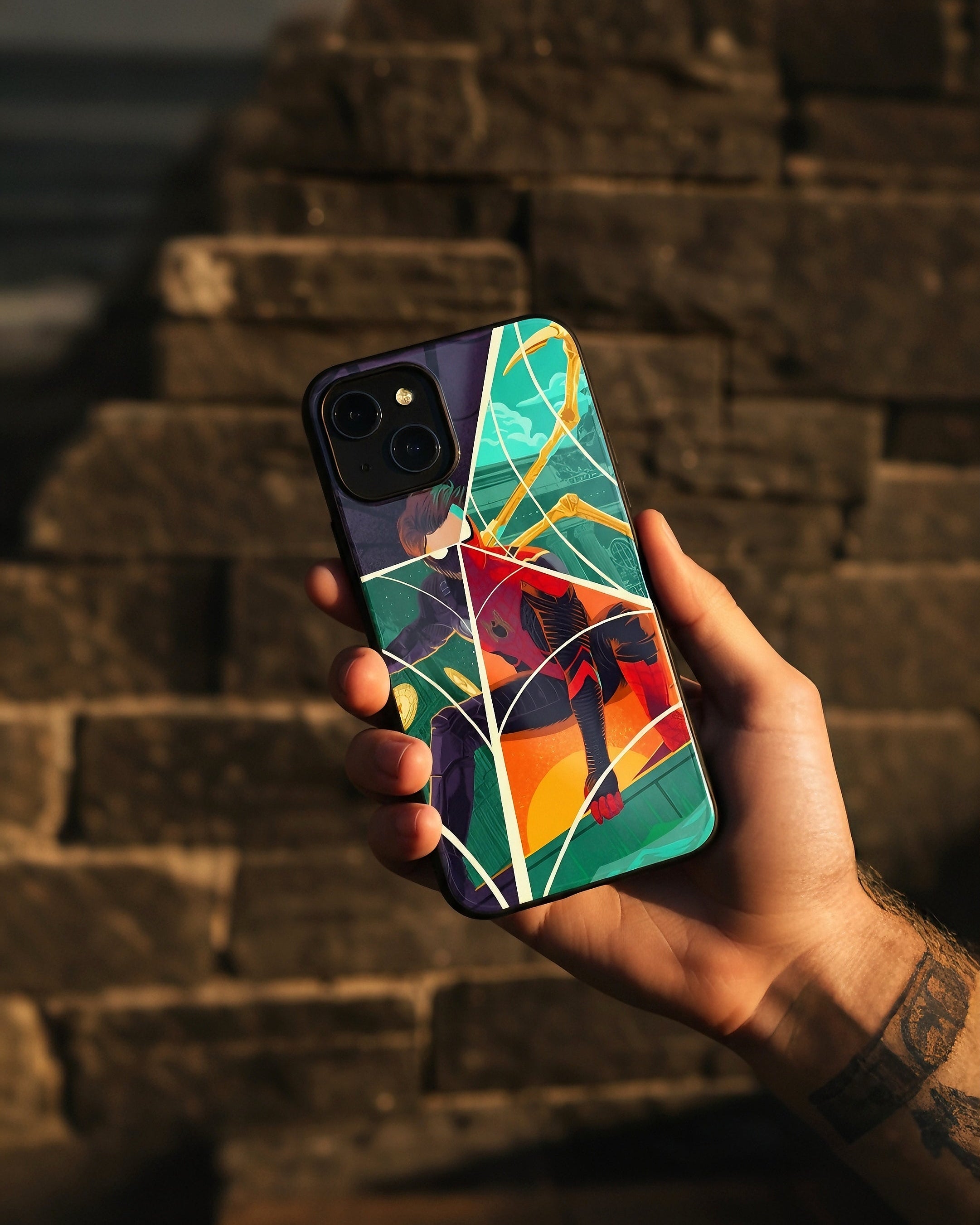 Hand holding a phone with a colorful case against a stone wall background