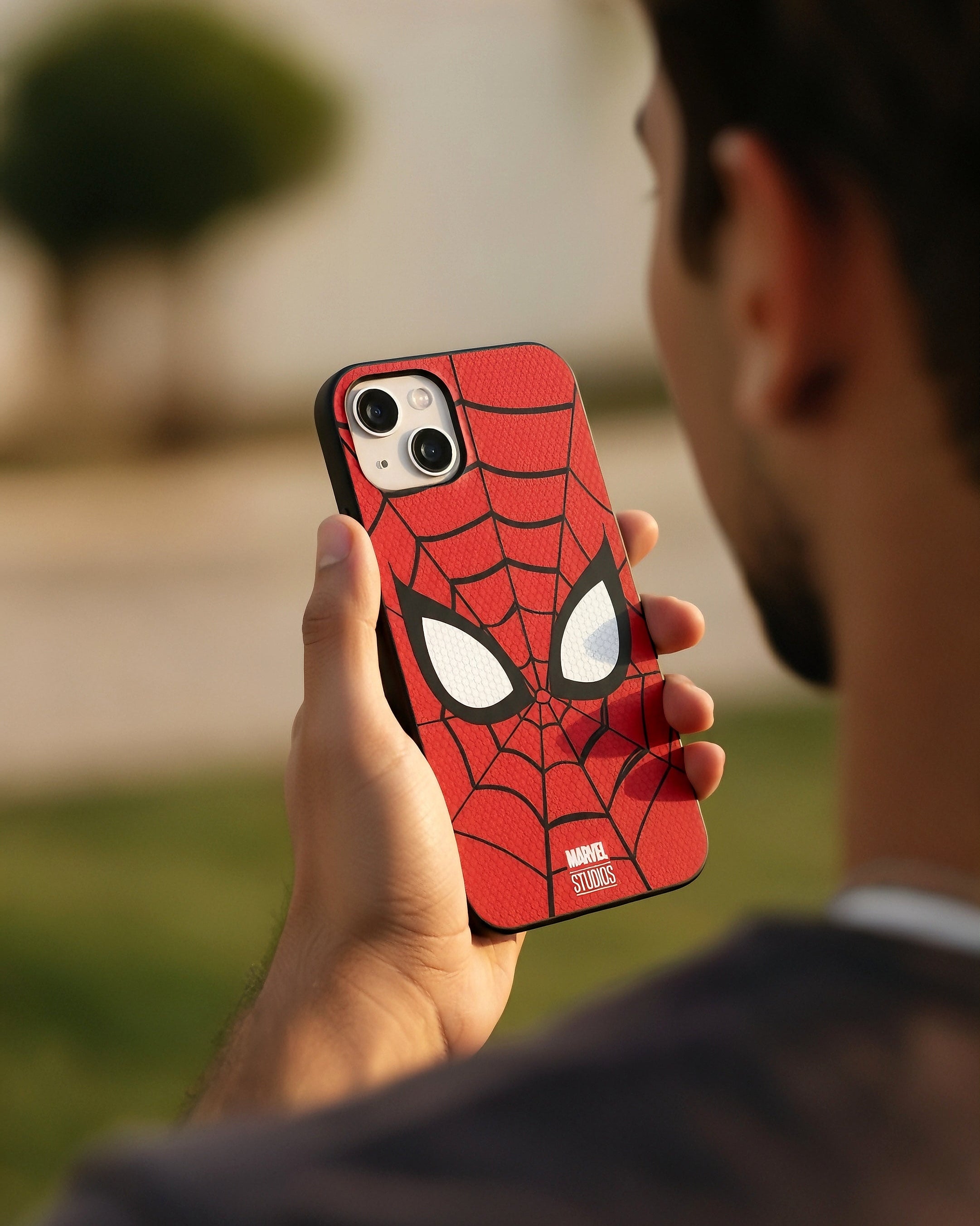 Person holding a phone with a Spider-Man case outdoors
